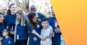 Group of diverse volunteers smiling and interacting with children in a park setting.