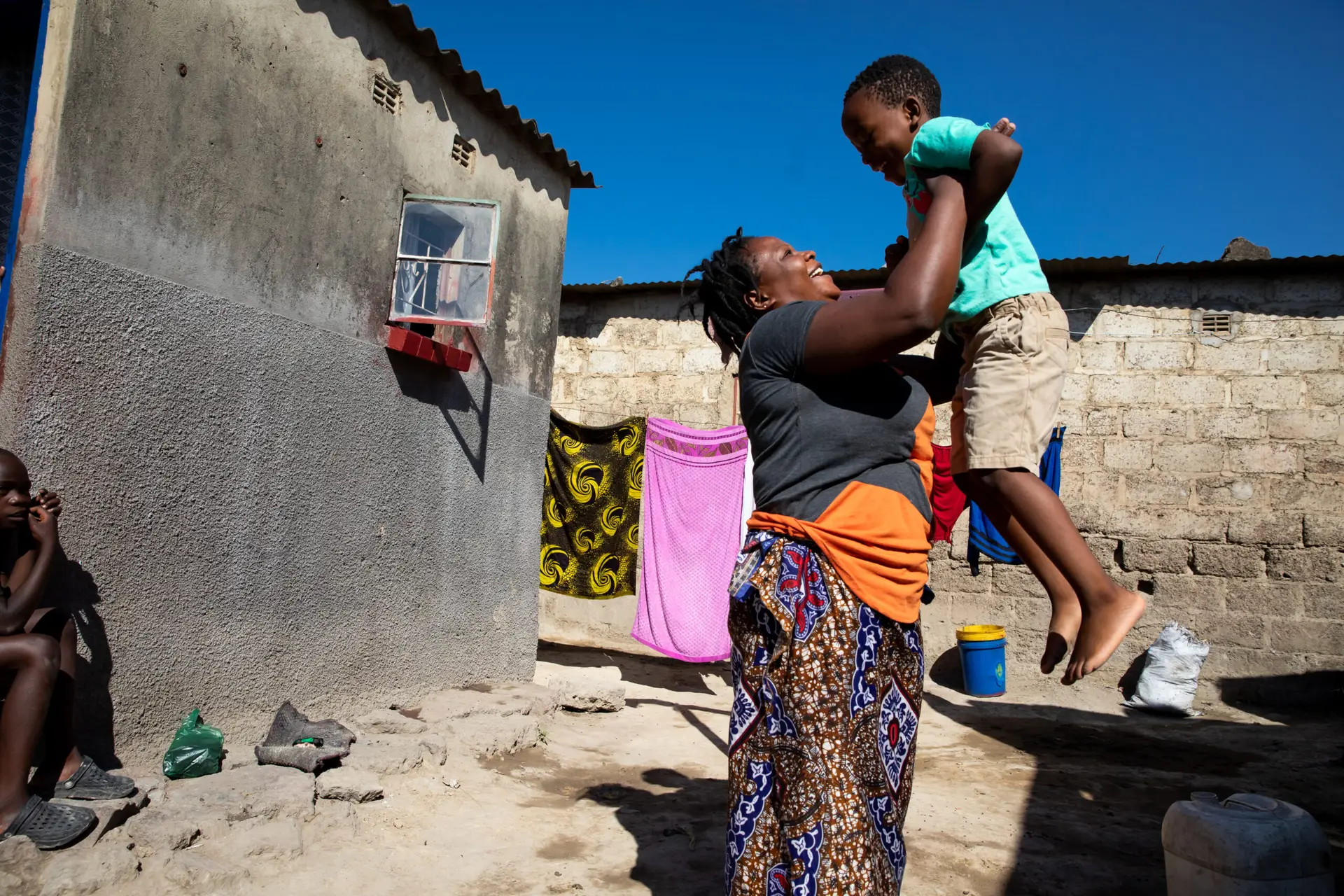 A woman lifts a young boy in a joyful moment outdoors.