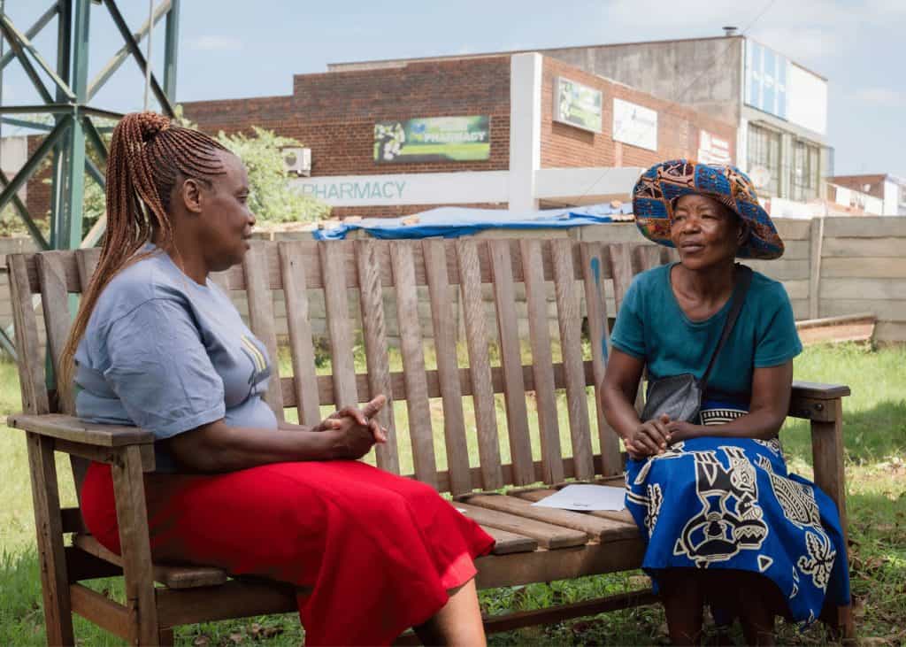 A client during a talk therapy session with a peer counsellor on a Friendship Bench.
