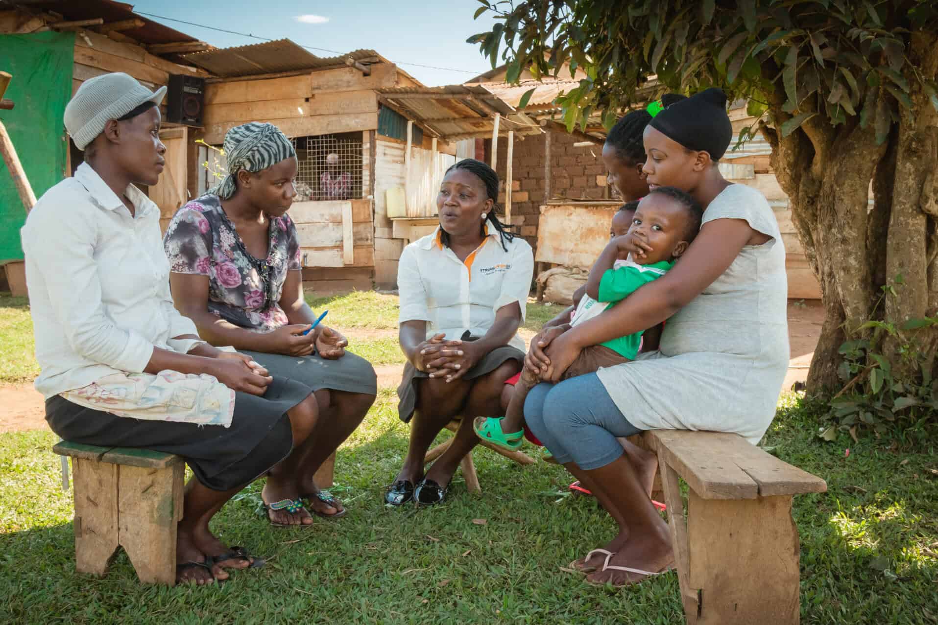 Women and children engaging in a health consultation outdoors.