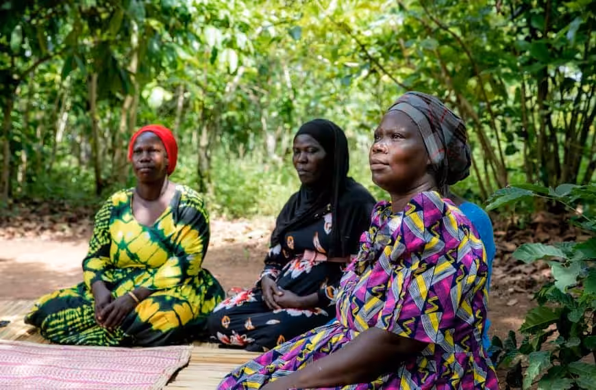 Three women sitting together as they take part in a StrongMinds therapy group session.