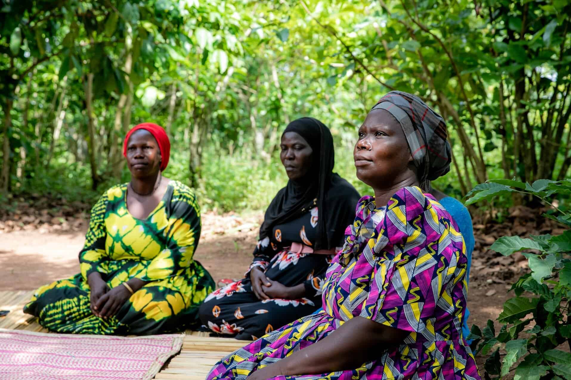 Three women sitting together as they take part in a StrongMinds therapy group session.
