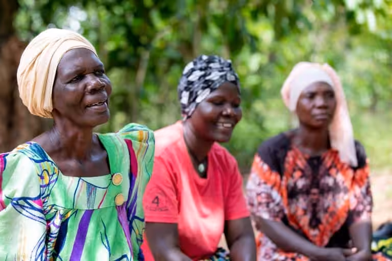 Three women taking part in a women's support group organised by StrongMinds.
