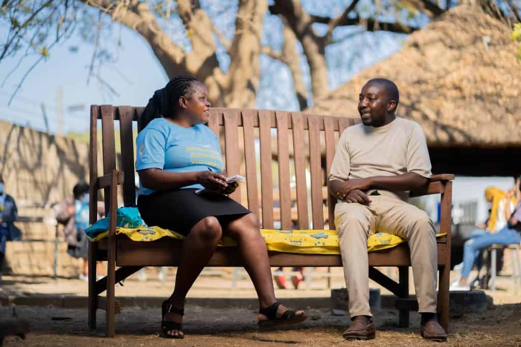 A man during a talk therapy session with a peer counsellor on a Friendship Bench in Zimbabwe.