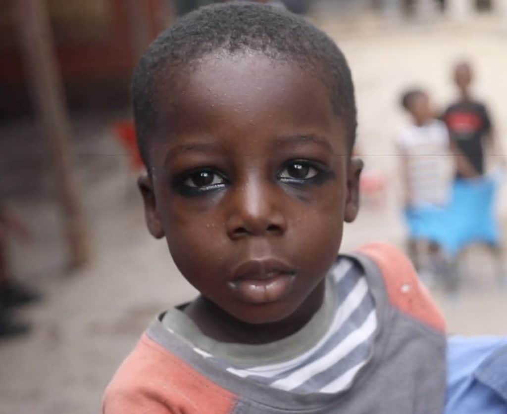 A young child wearing traditional chilo eyeliner in Ghana, gazing intensely into the camera.