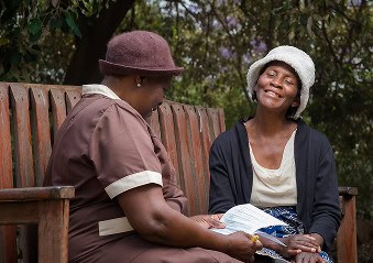 A woman during a talk therapy session with a peer counsellor on a Friendship Bench.