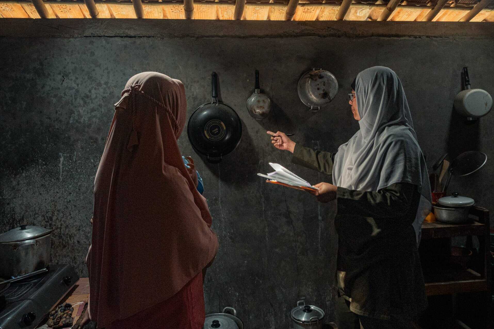 A woman conducts a home-based assessment in the kitchen of another woman's house in
Indonesia.