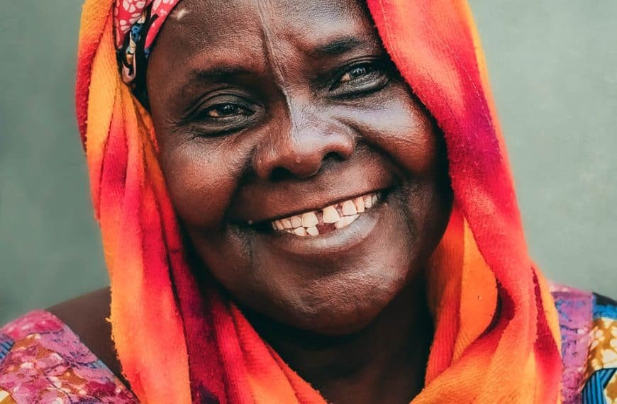 Smiling woman wearing colorful traditional dress and vibrant headwrap, radiating warmth and happiness.