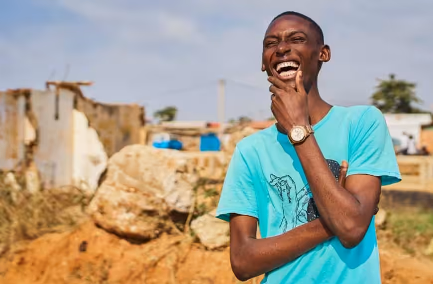 Happy man smiling and laughing, standing outside with construction in the background.