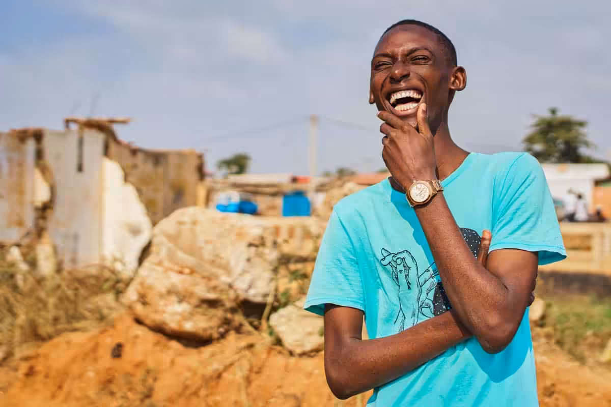 Happy man smiling and laughing, standing outside with construction in the background.
