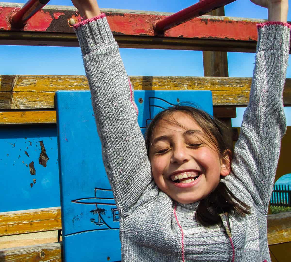 Happy girl enjoying outdoor play on colorful playground structures.