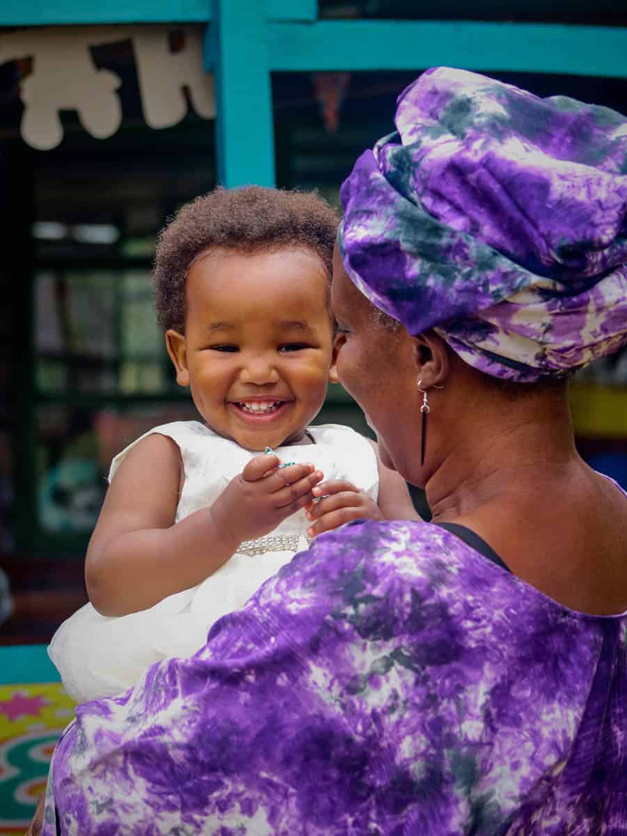 Smiling young girl and her mother sharing a joyful moment outdoors, highlighting love and happiness.