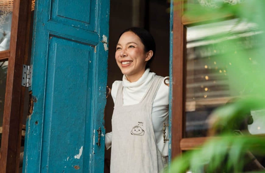 Happy woman smiling while standing at her cozy rustic home doorway.