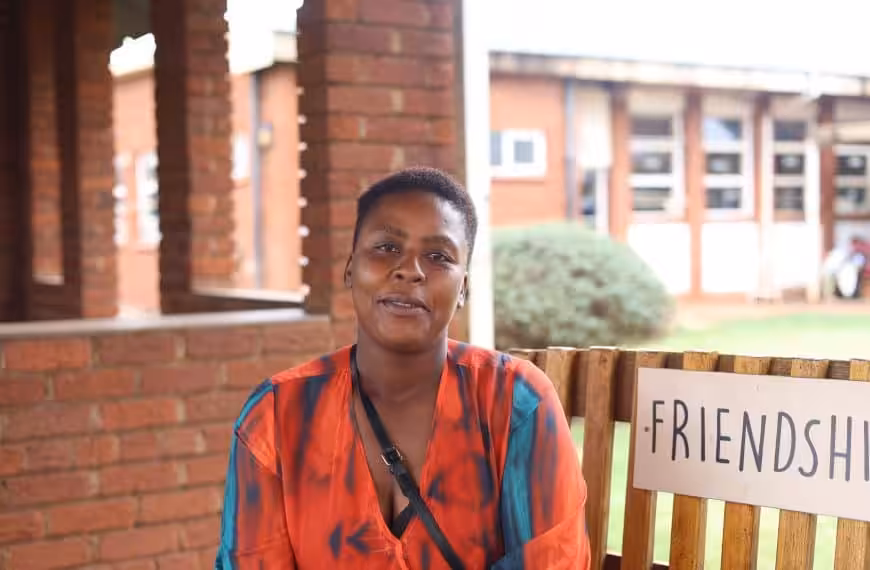 A woman helped by Friendship Bench, smiling on the bench