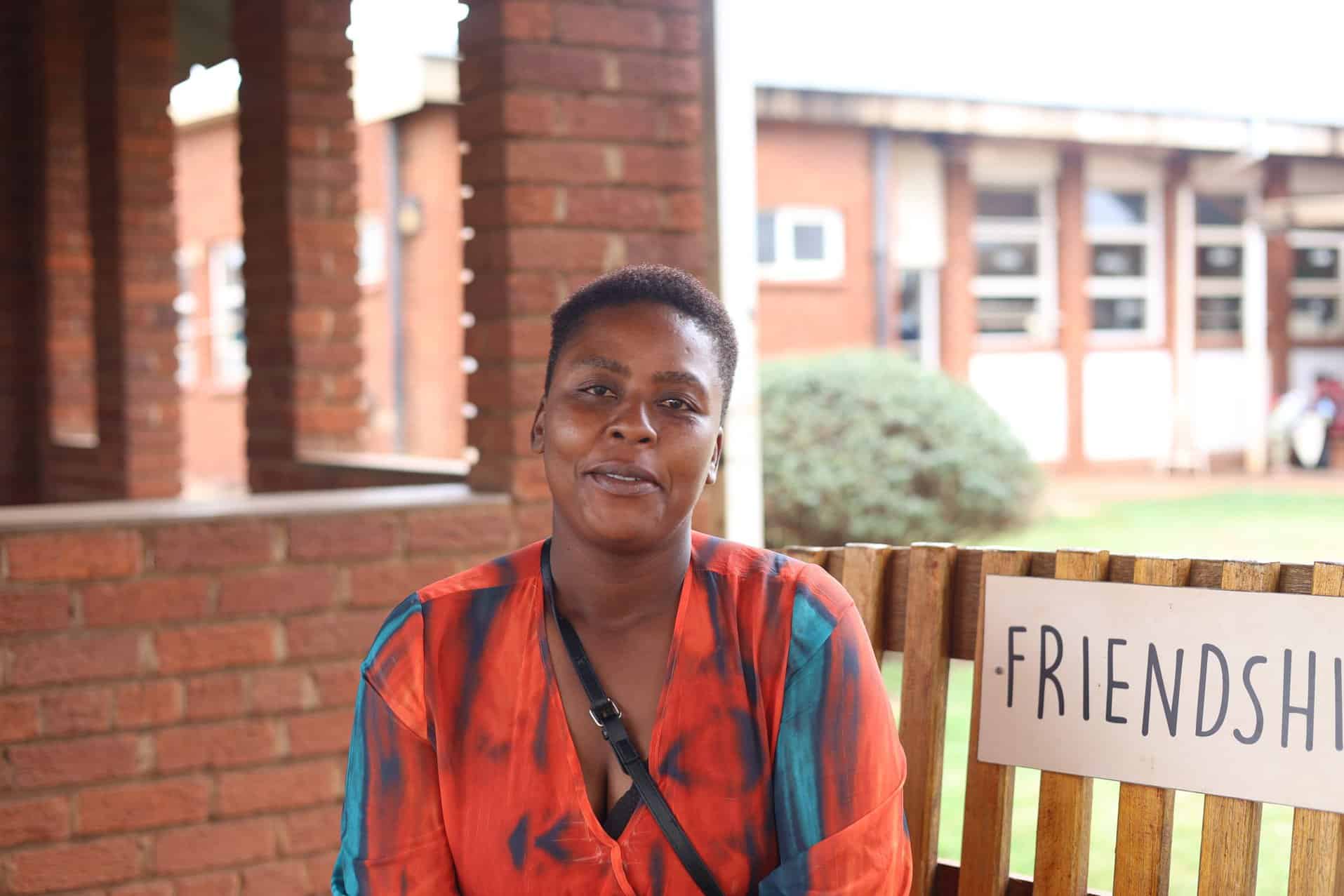 A woman helped by Friendship Bench, smiling on the bench