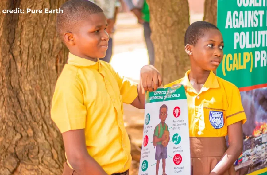 Two children in Ghana holding a sign that explains the effects of lead on the child.