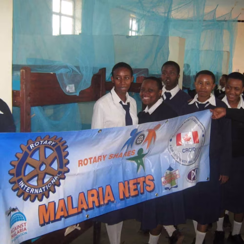 Happy students holding a banner about bed nets against malaria.