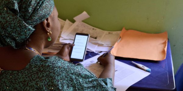 A woman going through the medical records of children Taimaka is helping at her desk.